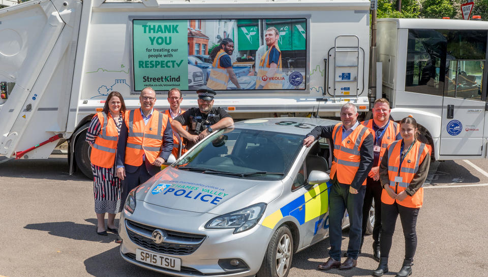 Veolia representatives and frontline staff stand with Buckinghamshire County Council officers, a Thames Valley Police Officer and the Thames Valley Police and Crime Commissioner, beside a police car and in front of a Veolia truck with the StreetKind logo on the side.