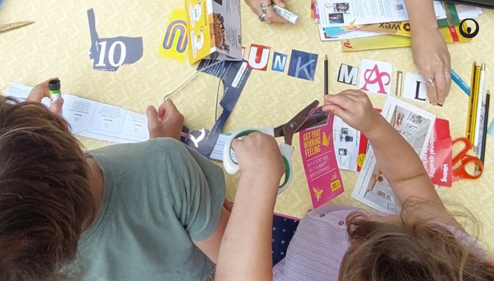 Image taken from above showing children's hands cutting up junk mail for a collage.