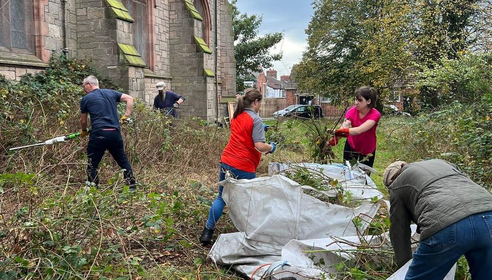 Volunteers doing garding outside a church in the outdoors. 