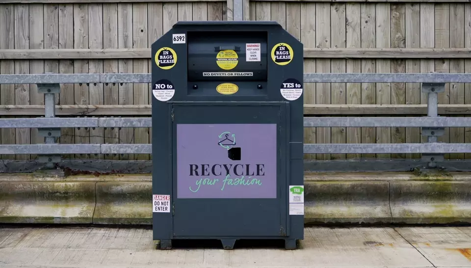 Image of a McArthurGlen textile bank against a wooden fence.