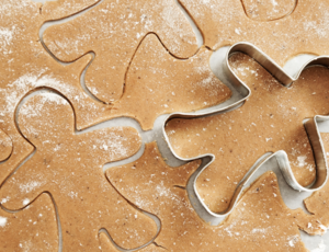 A cookie cutter in the shape of a human cuts out gingerbread biscuits