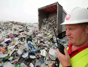 man standing outside a huge lorry load of litter 