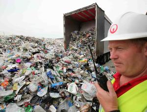 man standing outside a huge lorry load of litter 