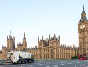 A Veolia Westminster collection vehicle drives over a bridge towards the Houses of Parliament
