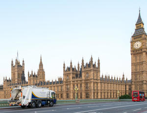 A Veolia Westminster collection vehicle drives over a bridge towards the Houses of Parliament