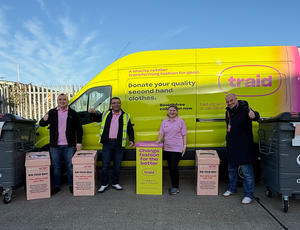 Veolia and Traid representatives stand in front of a Traid van alongside Against Breast Cancer collection boxes.