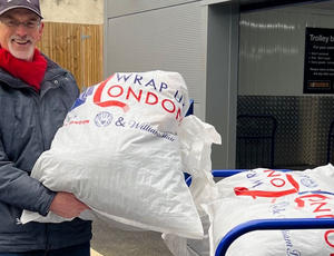 A man holds up a full bag of coats for donation.