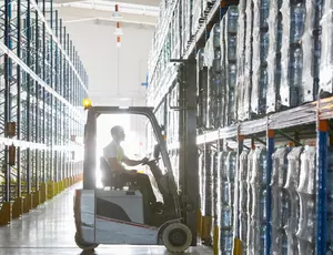 Forklift in warehouse picking up pallets of material