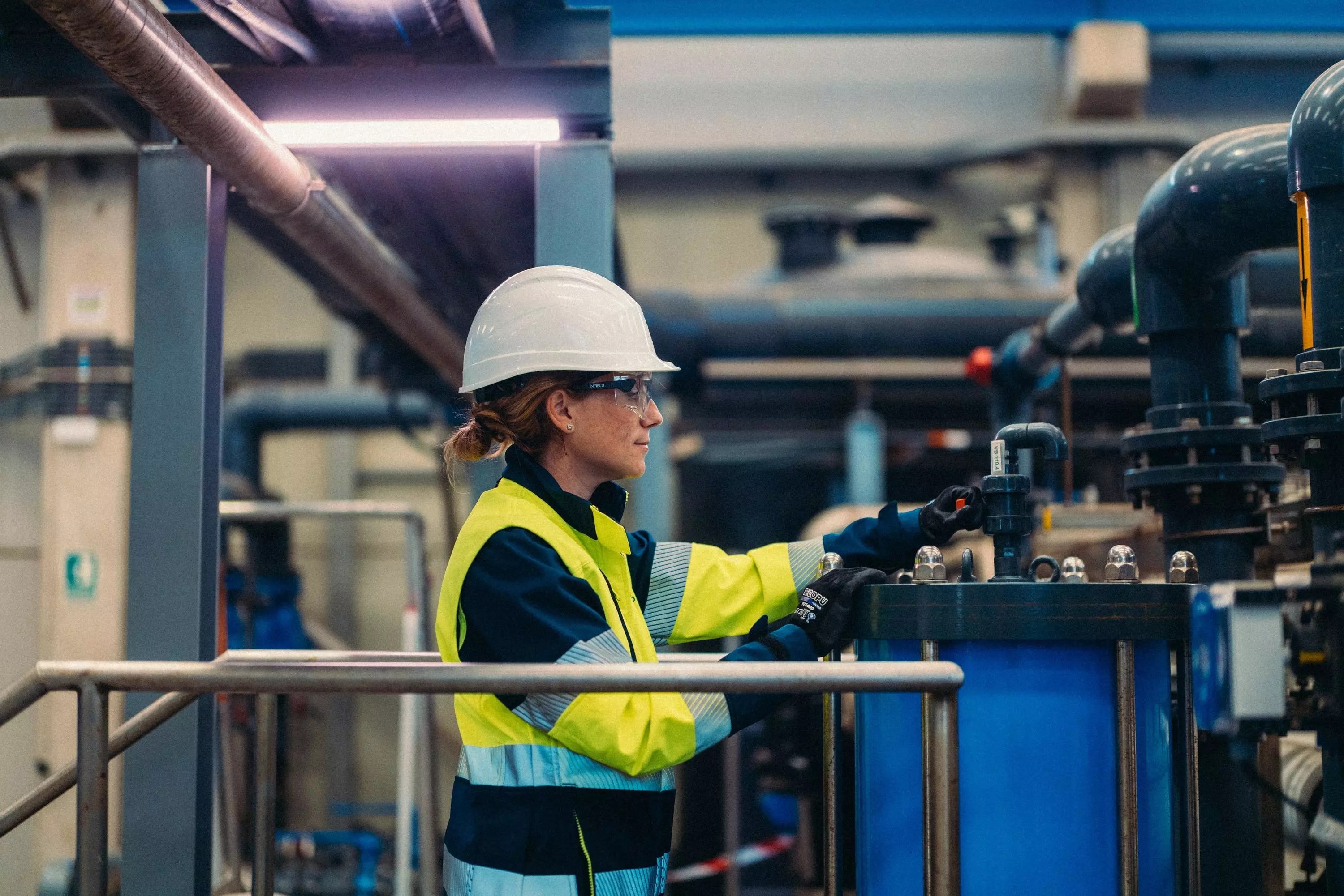 A Veolia operative in full PPE monitors a dial in a warehouse.
