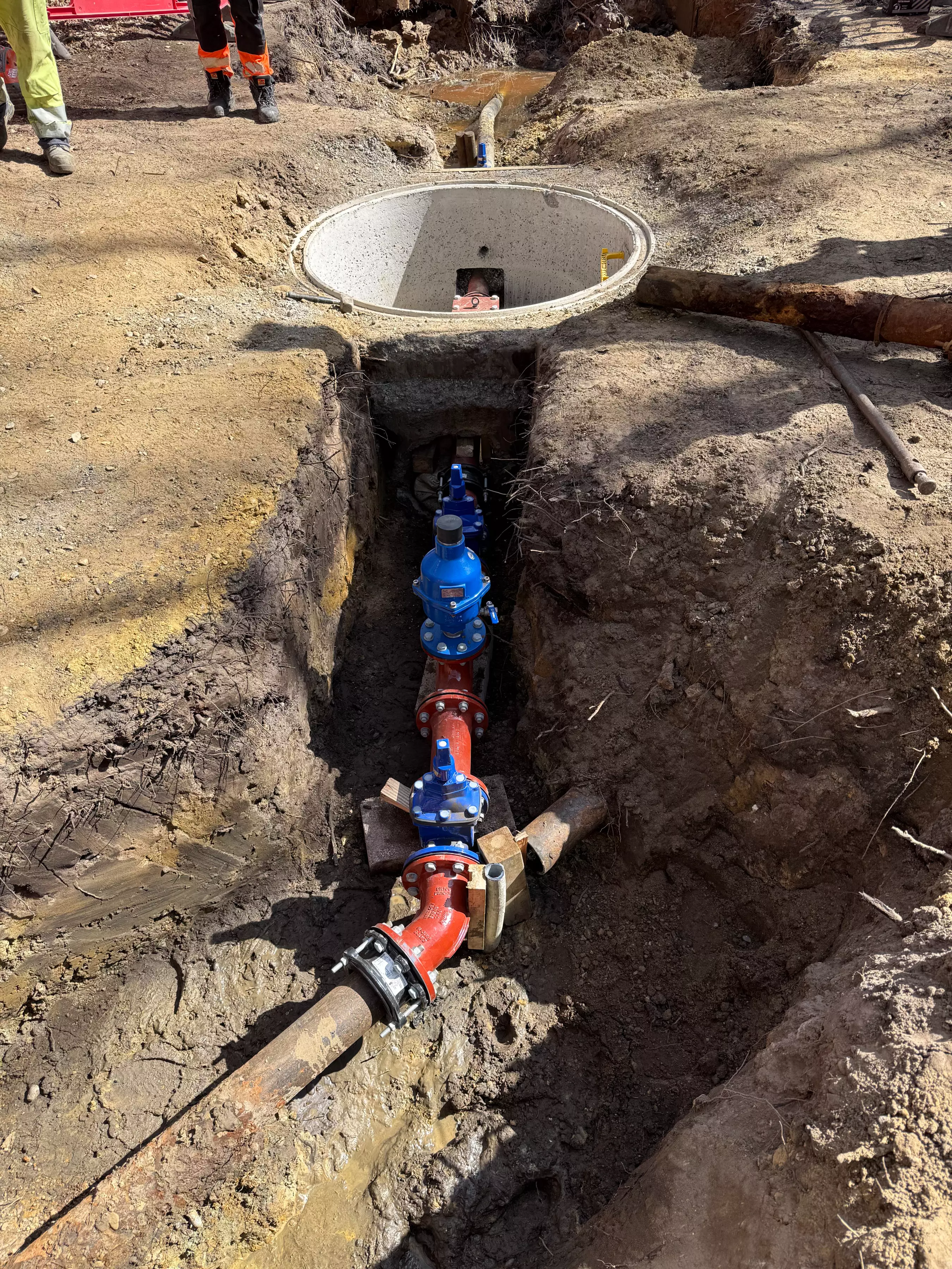An image of a trench with a pipe network being constructed below ground.