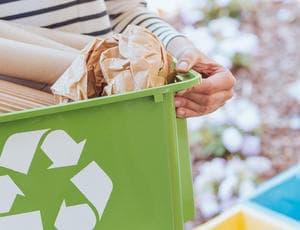 recycle logo on a bin with rubbish surrounding it 