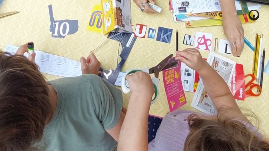 Image taken from above showing children's hands cutting up junk mail for a collage.