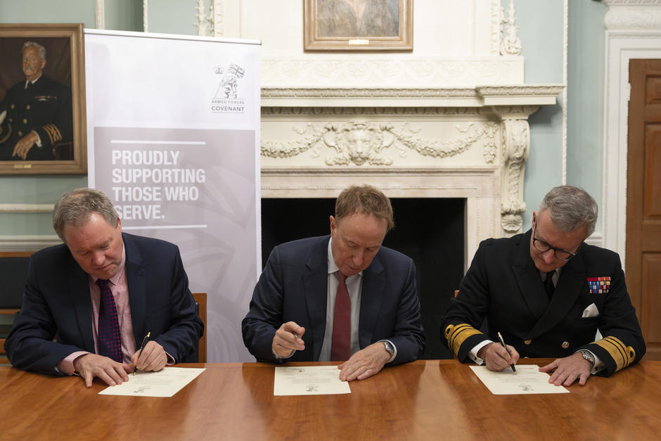 three people signing documents in formal attire