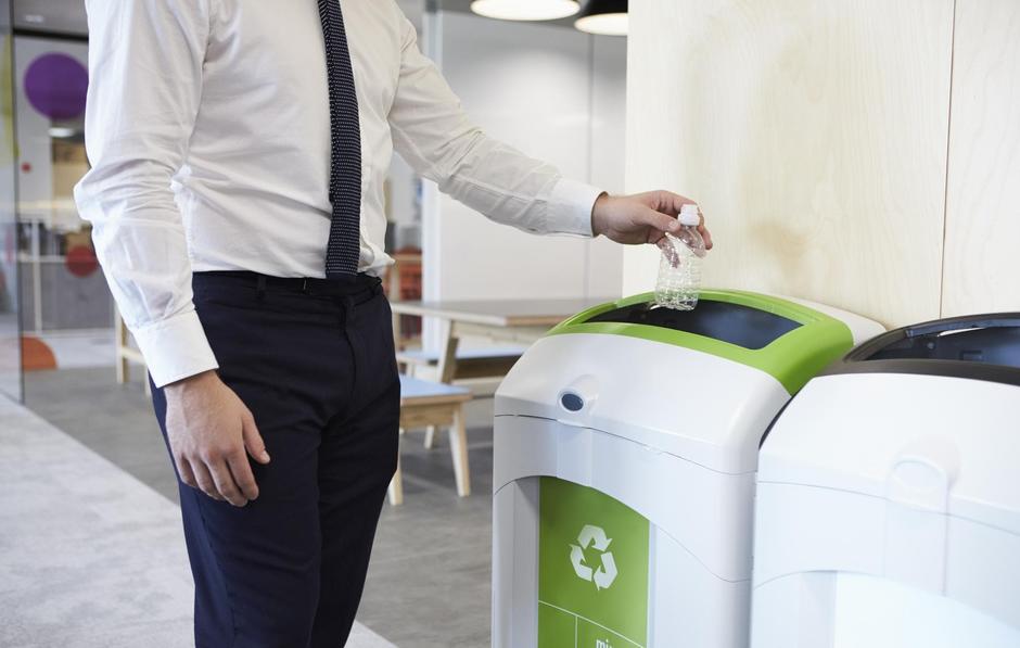Man placing plastic bottle into recycling bin