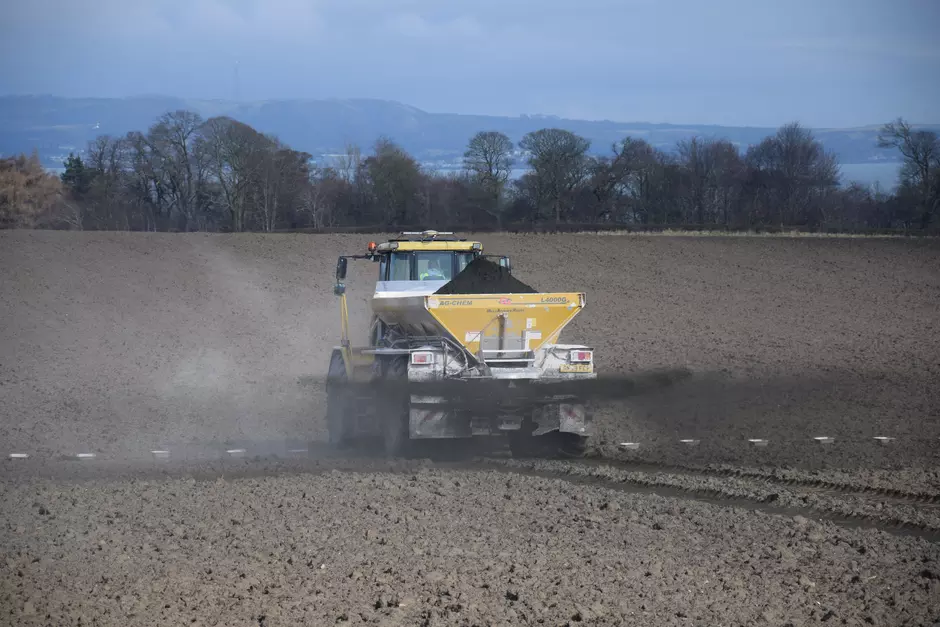 Tractor spreading very small rock particles