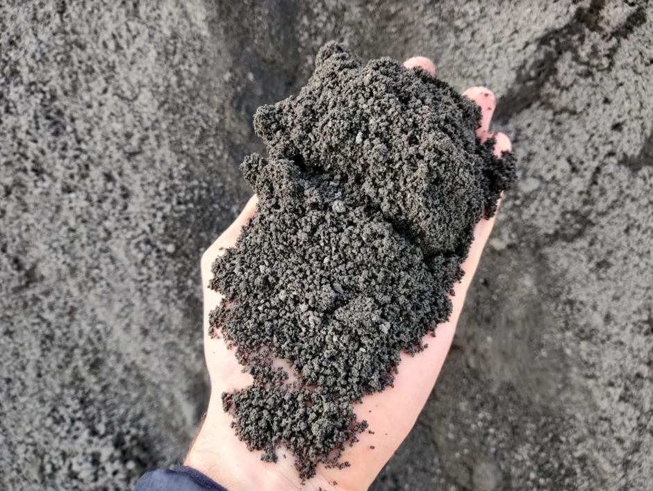 Hand holding ground soil after spreading very small rock particles