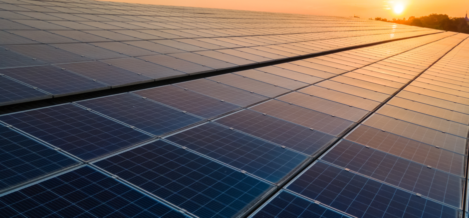 The photo shows solar panels with the sun setting in the background.