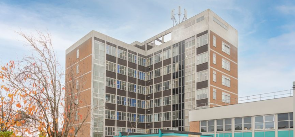 The photo shows a tall building in front of a blue sky.