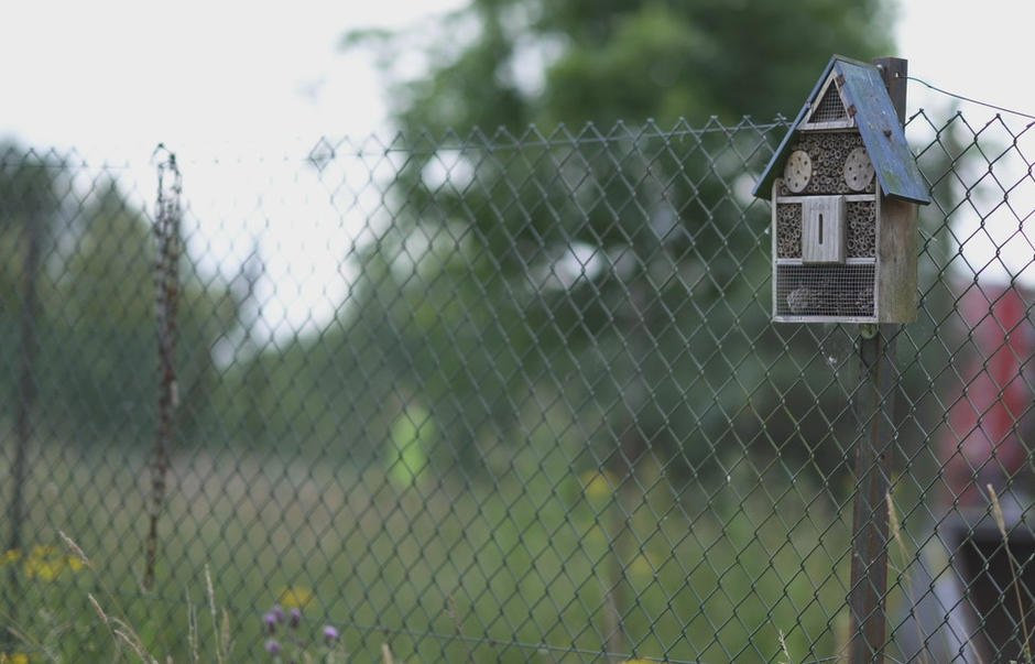 A bug hotel is attached to a fence