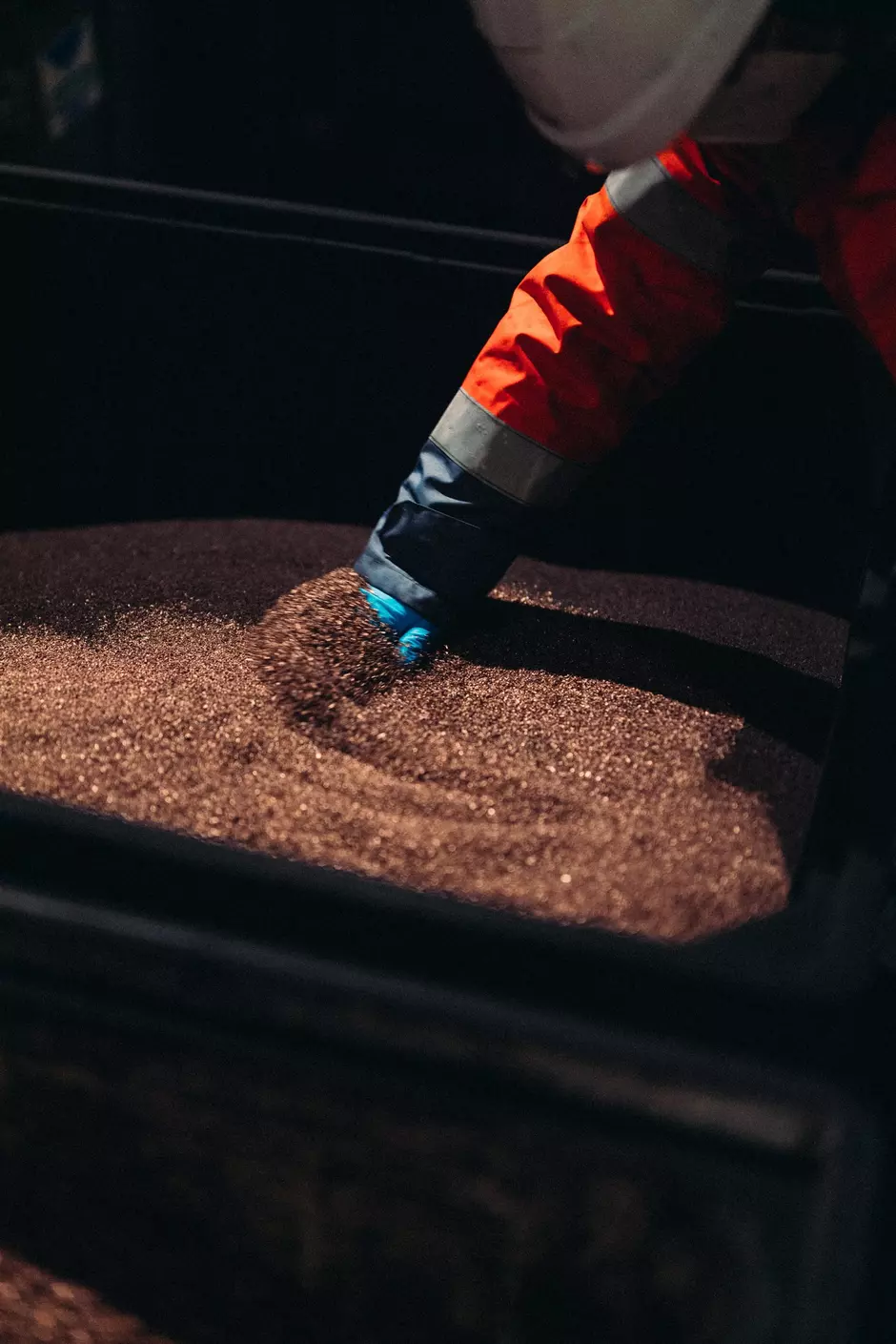 A gloved hand sifts through recycled copper.