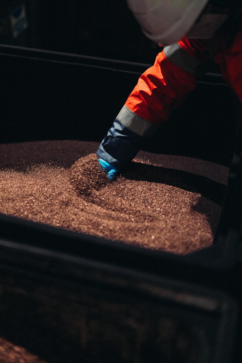 A gloved hand sifts through recycled copper.