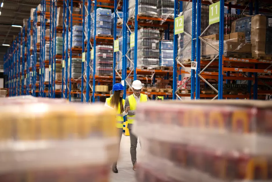 Two people in hivis walking through a distribution centre