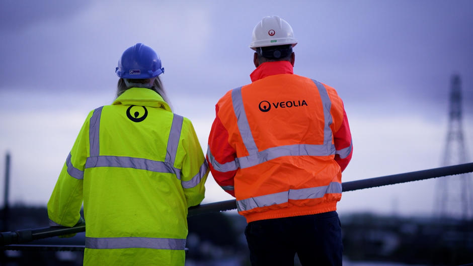 Two Veolia operatives in branded hi-vis stand with their backs to the camera.