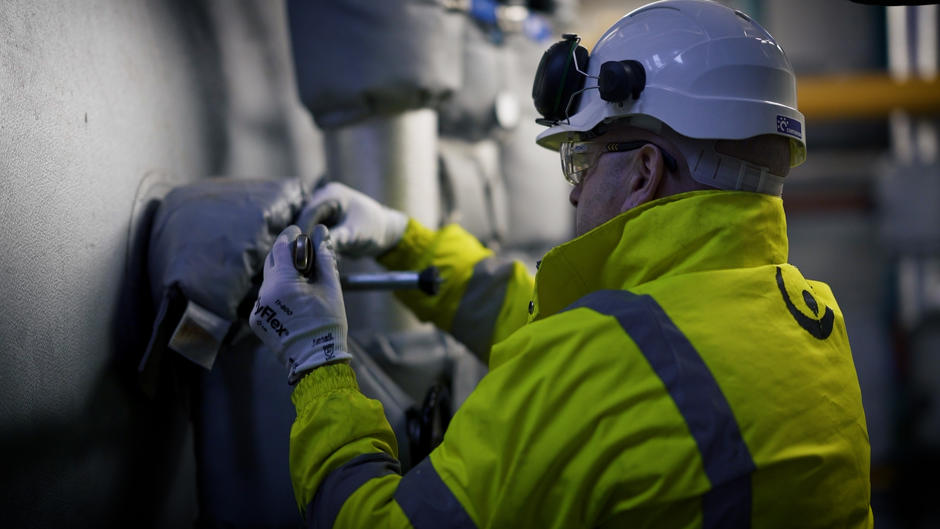 A Veolia operative turns a valve on the boiler.