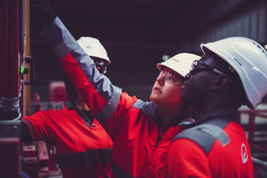 Veolia operatives in hard hats, point at a dial on a piece of machinery.