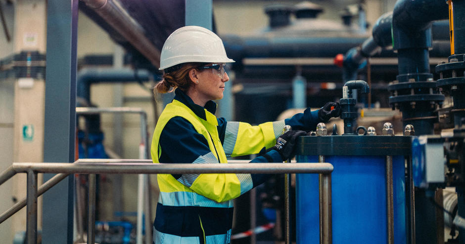 A Veolia operative in full PPE monitors a dial in a warehouse.