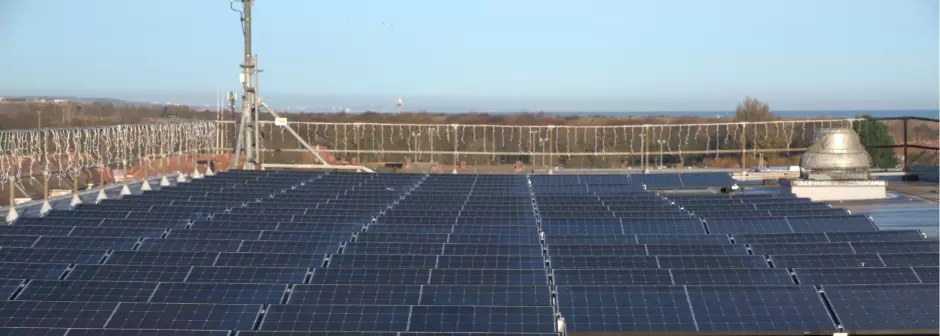 A rooftop full of solar panels, looking out across the surrounding buildings.
