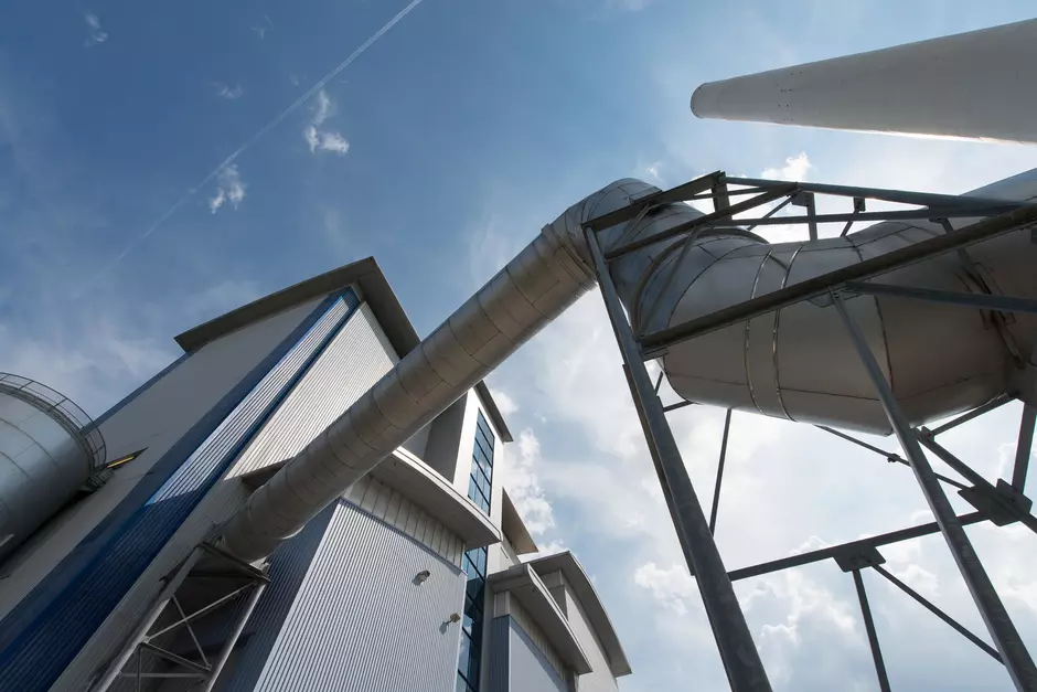 A photo taken from the ground looking up at a large district heating pipe against a blue sky.
