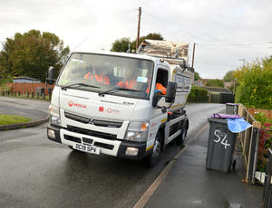 image of truck on residential roads with bins on the pavement