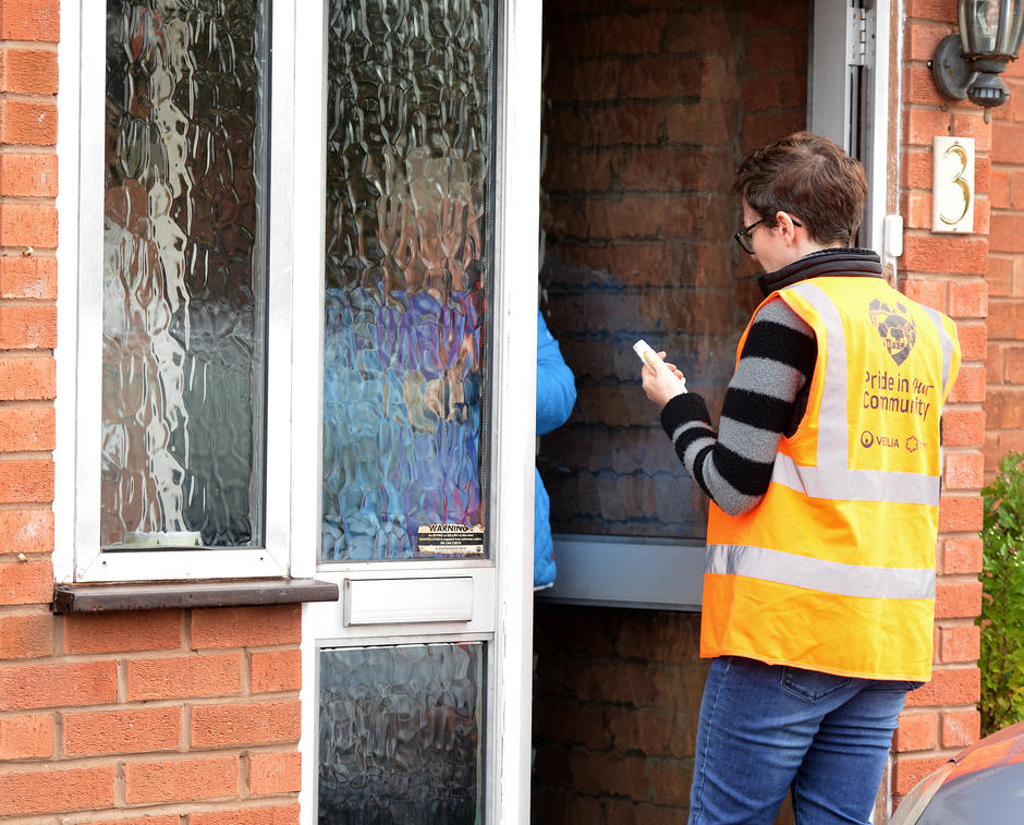 Photo of woman in a hi viz vest talking to a resident at the doorstep