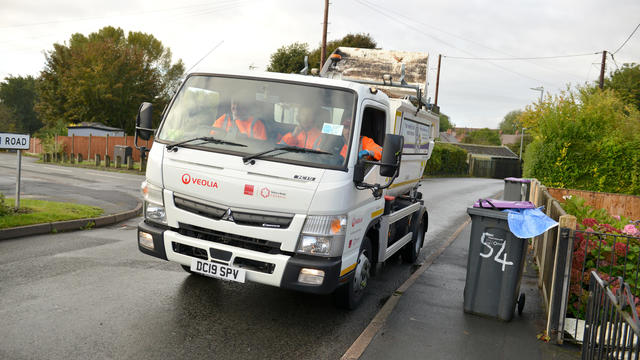 image of truck on residential roads with bins on the pavement